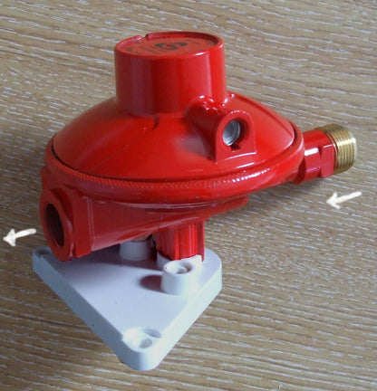 red propane gas regulator with wall mount attached.